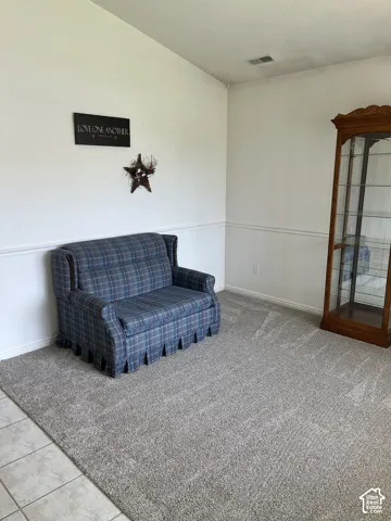 Neutral-toned carpeting, white walls with chair rail molding, and a tiled entry