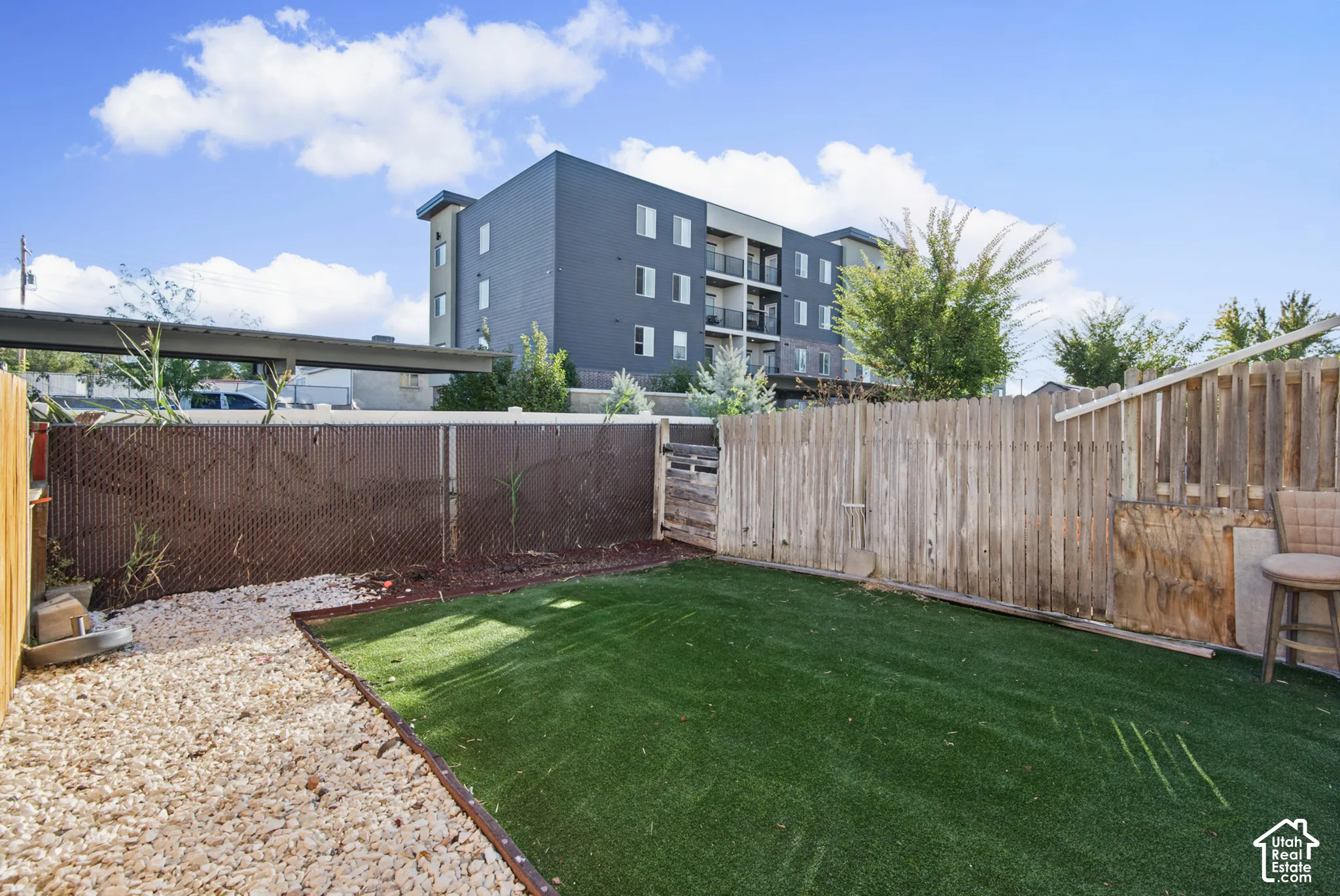 Enclosed yard featuring artificial turf, gravel pathway, and privacy fencing