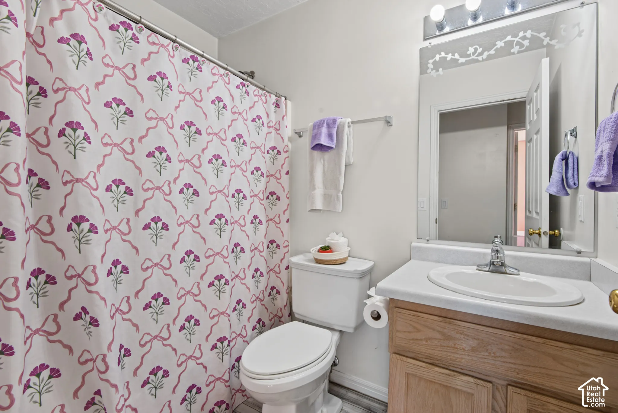 Bathroom with a wood-finish vanity, integrated sink, and wall-mounted mirror