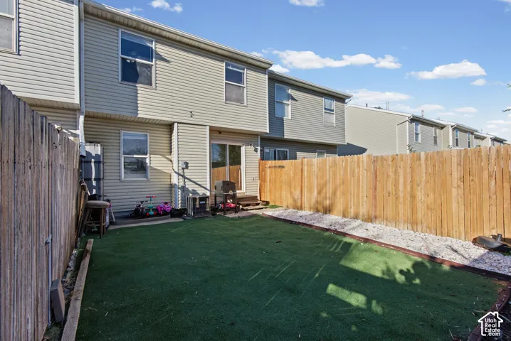 Fenced backyard featuring artificial turf, a white rock border, and a sliding glass door