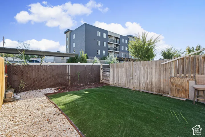 Enclosed yard featuring artificial turf, gravel pathway, and privacy fencing