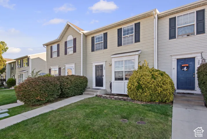 Two-story townhome with light-colored siding and dark shutters