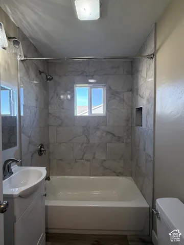 Tub with a shower system featuring gray-patterned tile surround