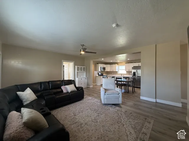 Open-concept living space with wood-finish flooring, a ceiling fan, and recessed lighting