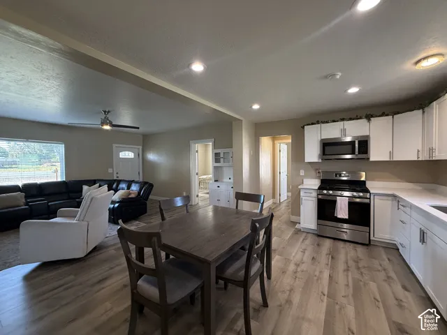 Open-concept kitchen and living area featuring wood-finish flooring, recessed lighting, and a ceiling fan