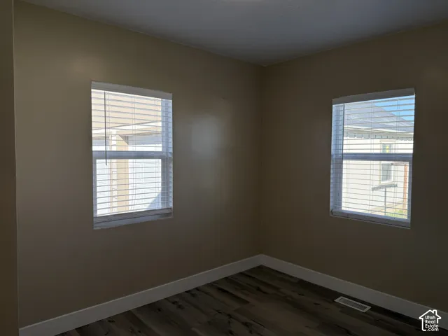 Recessed windows with blinds, wood-finish flooring, and light-toned walls