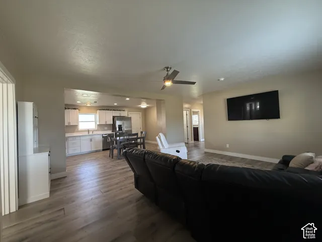 Open-concept living space with wood-finish flooring, a ceiling fan with integrated lighting, and recessed lighting