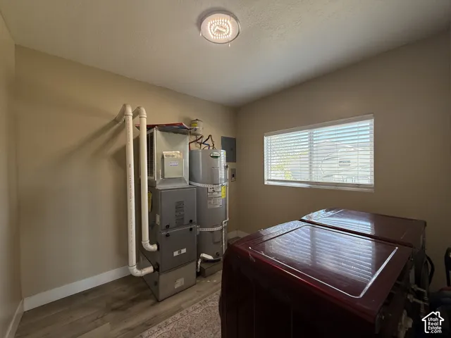 Utility area featuring a water heater, furnace system, and wood-finish flooring