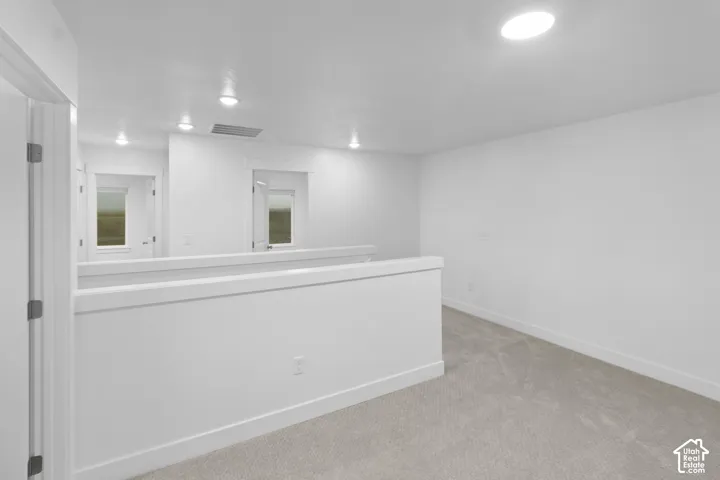 Neutral tone carpeting with white baseboards and walls