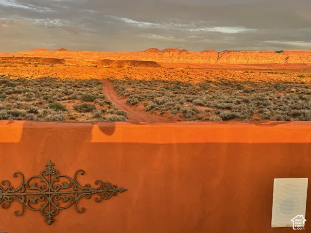 Earthy orange stucco wall featuring an ornate metal accent and a desert landscape with distant rock formations