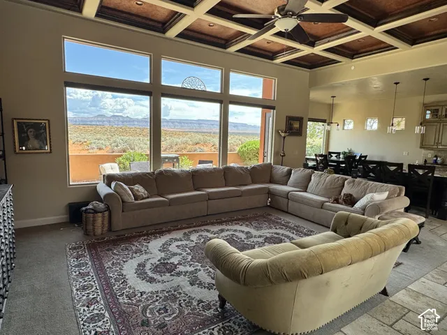 Expansive windows showcasing desert scenery, coffered ceiling with a ceiling fan, recessed lighting, and tile flooring