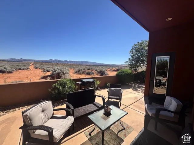 Paved patio area with a privacy wall, featuring a clear glass-paneled door, and a desert landscape beyond