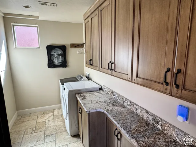 Extensive cabinetry with dark hardware, stone-finish countertops, tiled flooring, and a fixed window