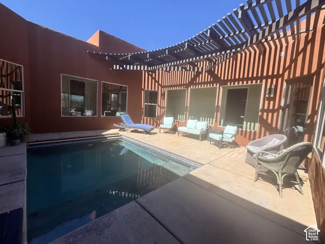 Private courtyard with a built-in swimming pool, extended patio, and a slatted pergola