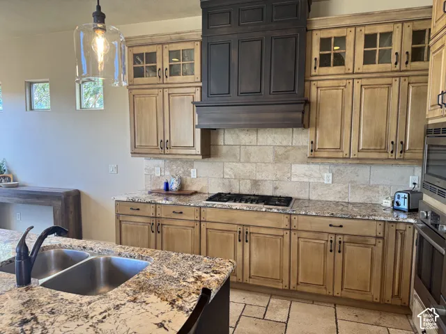 Kitchen featuring extensive wood cabinetry, granite countertops, a built-in gas range, and a stone tile backsplash