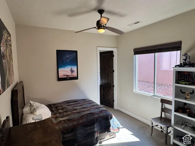 Window with horizontal blinds, ceiling fan with integrated lighting, wood-finish door, and carpeted flooring