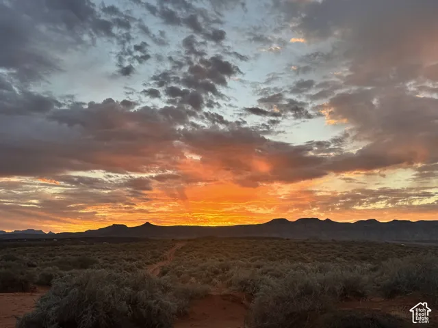 Expansive desert landscape featuring distant mountain formations and a vibrant, multicolored sky