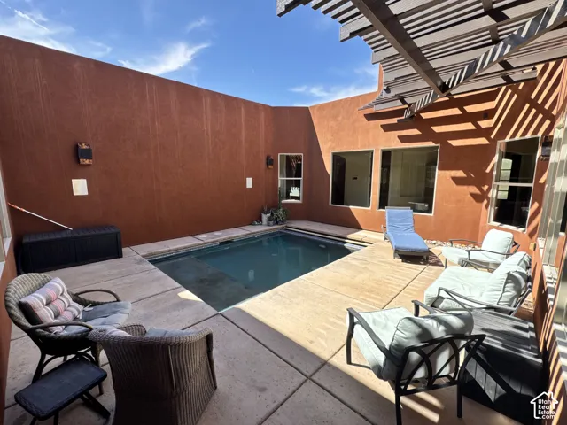 Private courtyard featuring a swimming pool, concrete patio, and a wood-slat pergola