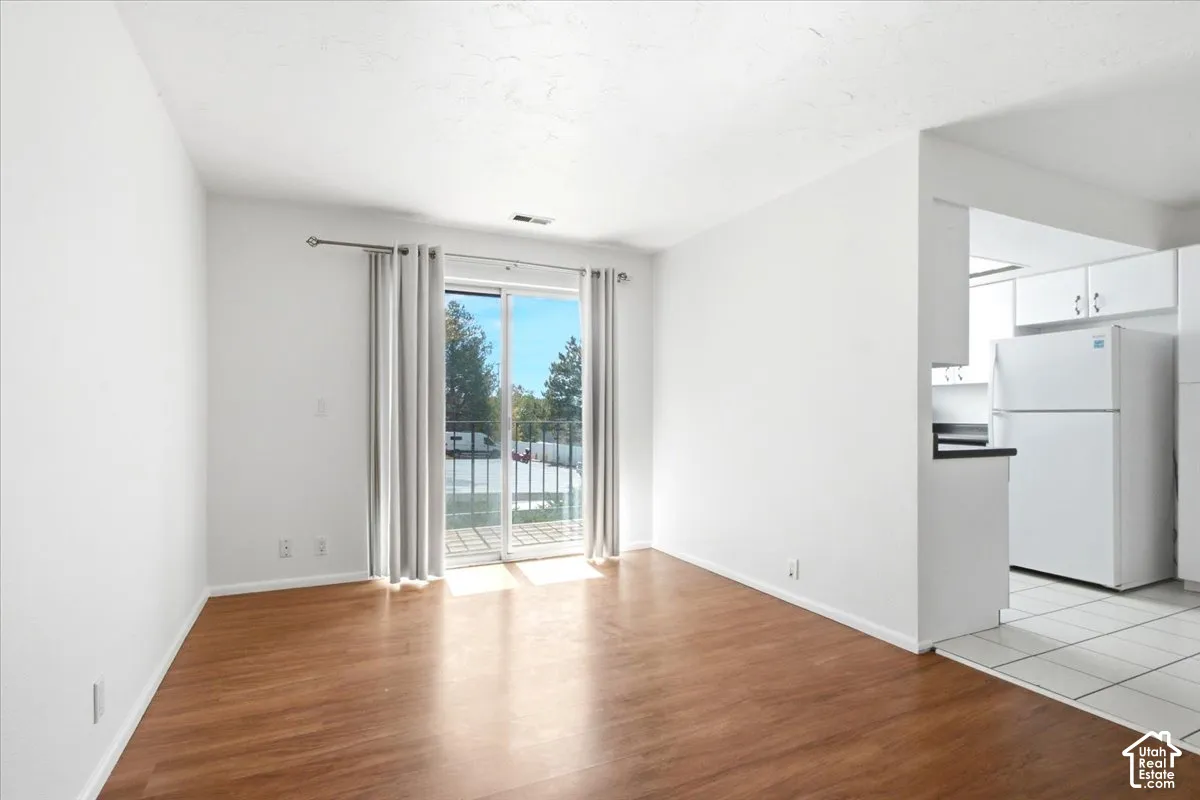 Wood-finish flooring throughout, bright white walls, and a sliding glass door with balcony access