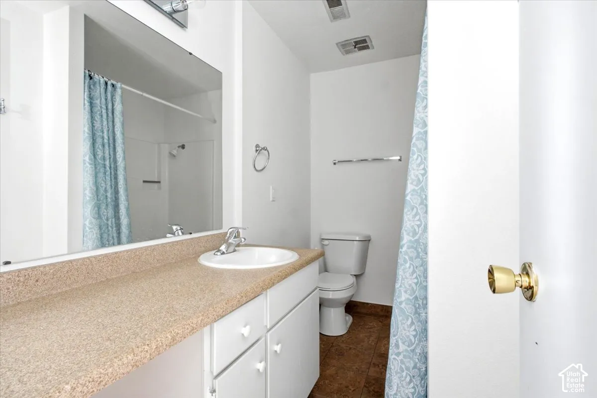 White vanity cabinetry with a large countertop, single basin sink, and a wall-mounted mirror