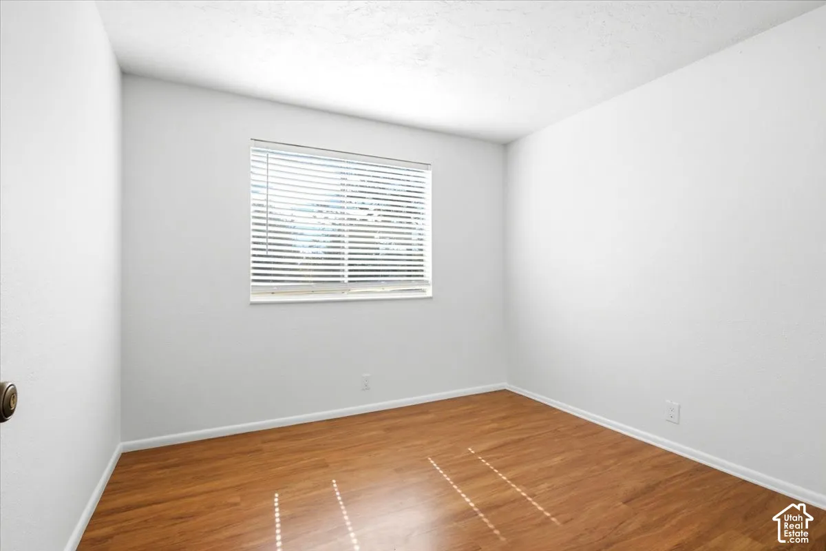 Wood-finish flooring with crisp white walls and window blinds