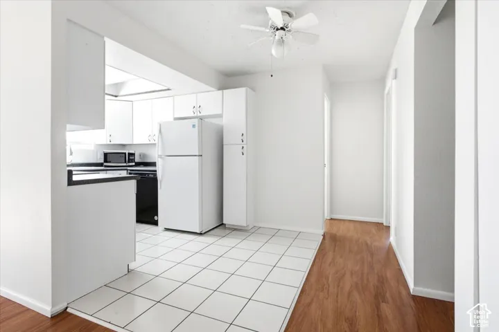Kitchen featuring white cabinetry, black countertops, white tile flooring, and integrated appliances