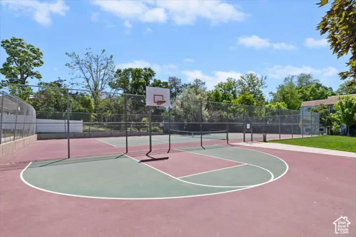 Sport court featuring a basketball hoop, tennis net, and perimeter fencing