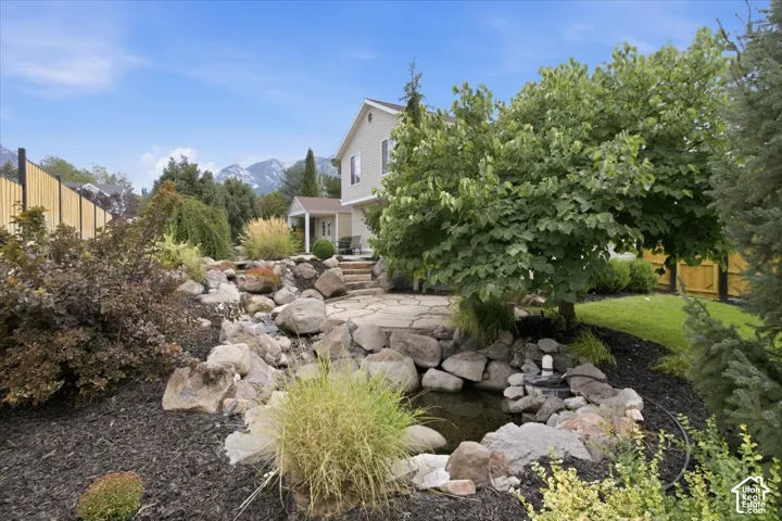 Manicured landscaping featuring a stone pathway, rock garden, and water feature
