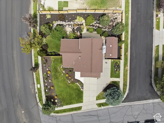 Property featuring a brown shingle roof, paved driveway, and concrete walkways