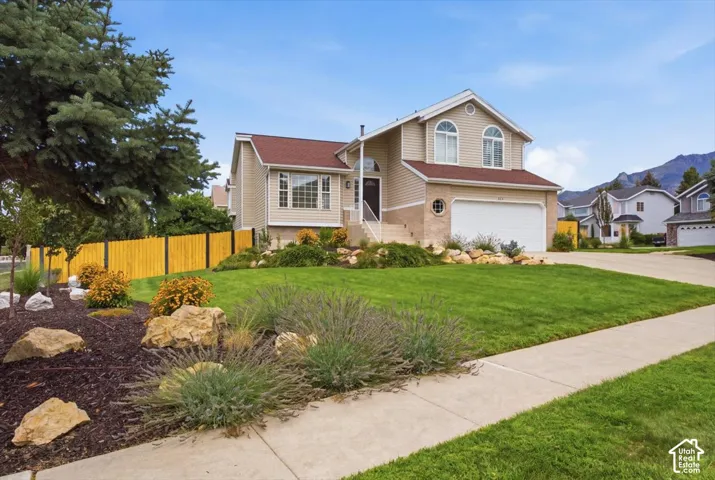 Two-story residence with a red-shingled roof, beige siding, and a two-car garage