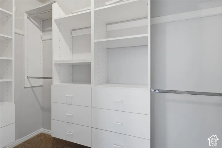White built-in closet system featuring multiple shelves, integrated drawers, and metal hanging rods