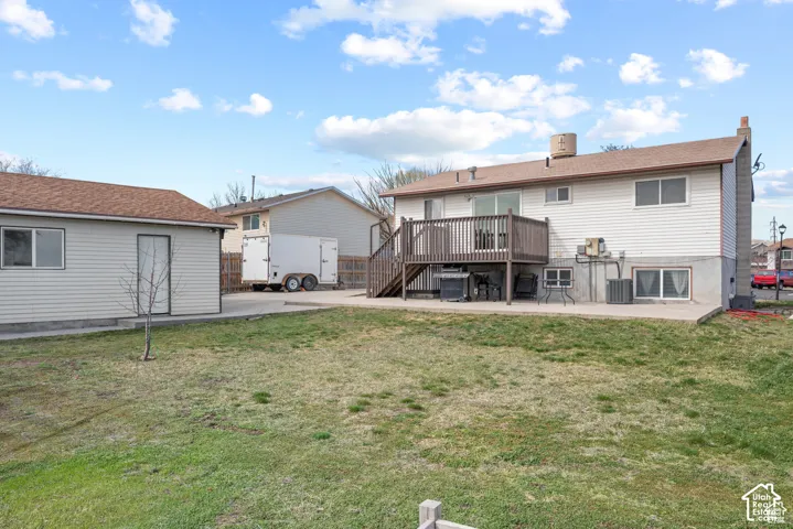 Expansive backyard with a detached accessory building, concrete patio, and a wood deck