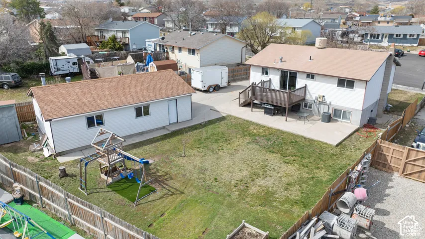 Expansive backyard with a large concrete patio, wood deck, and detached auxiliary building