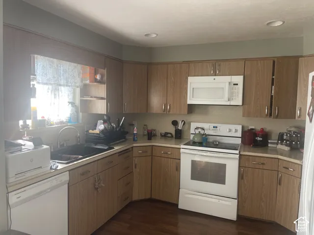 Kitchen featuring wood-finish cabinetry, white appliances, recessed lighting, and a dual-basin sink with a gooseneck faucet