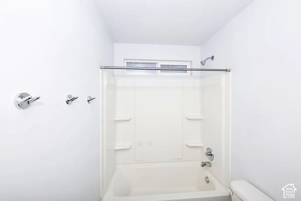 Bathroom featuring a composite tub and shower surround with integrated shelving, chrome fixtures, and a horizontal transom window
