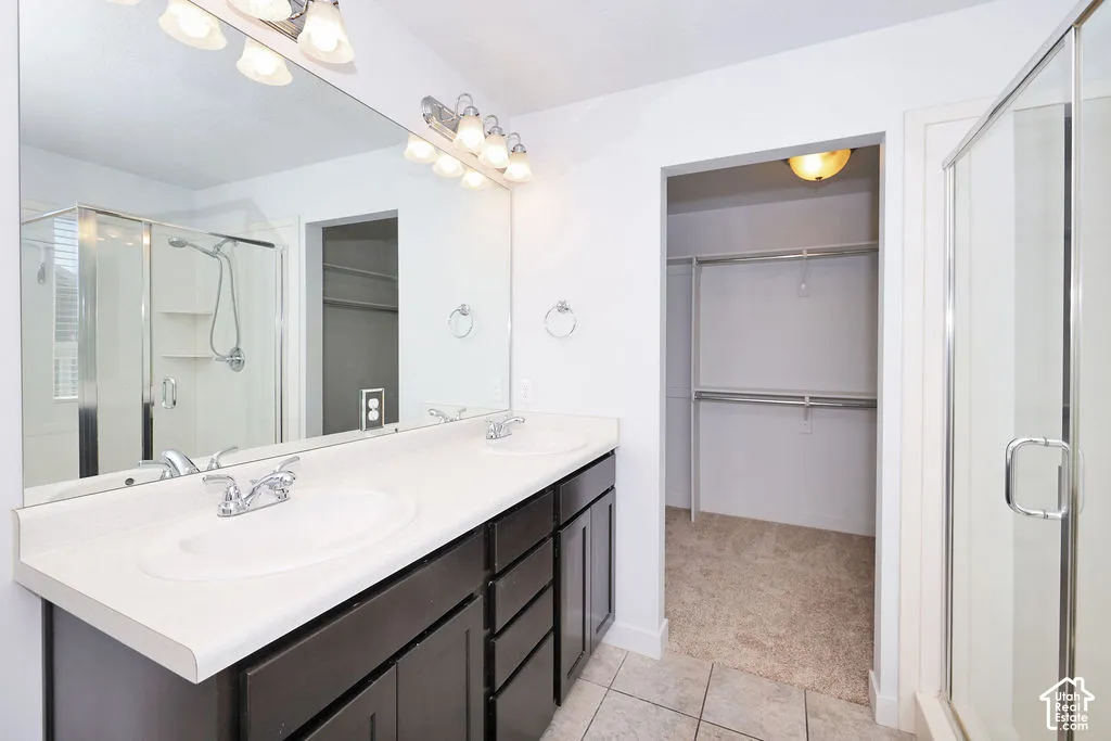 Dual vanity featuring dark cabinetry, light-toned countertops, two inset sinks, full-width mirror, and a glass-enclosed shower