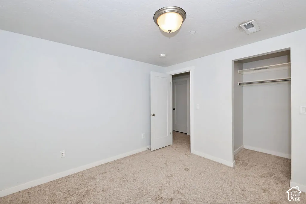 Neutral-toned wall paint, wall-to-wall carpeting, semi-flush mount ceiling lighting, and a reach-in closet featuring built-in shelving and a metal hanging rod
