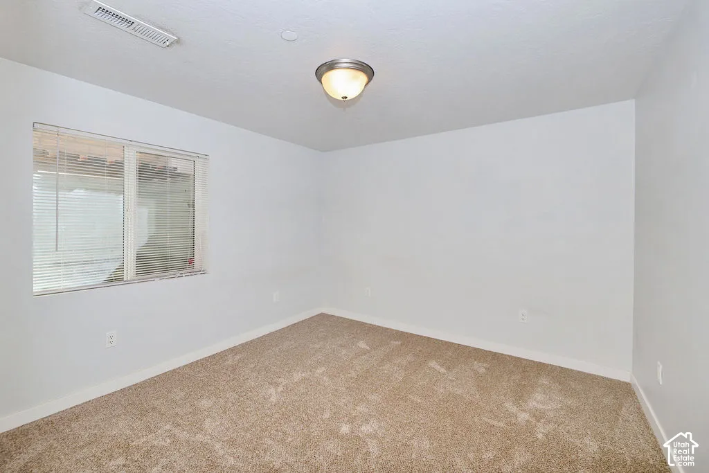 Neutral-toned carpeted flooring, window with installed horizontal blinds, and a semi-flush mount light fixture