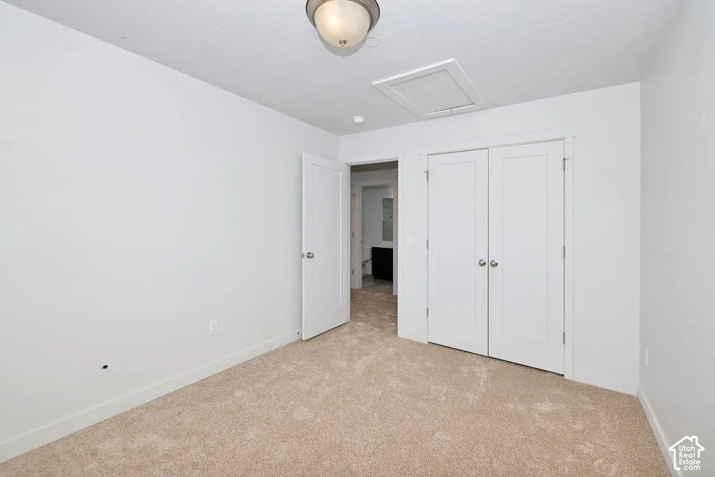 Neutral-toned wall-to-wall carpeting, double-door closet with recessed paneling, and flush-mount overhead lighting