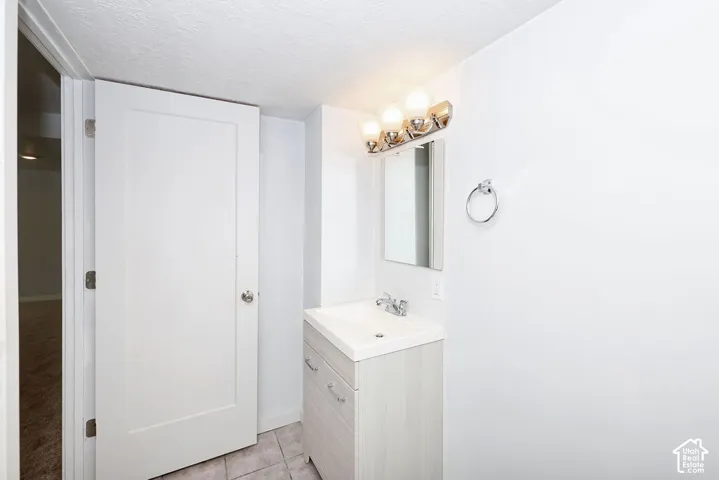 White vanity with an integrated sink and chrome faucet, under a rectangular mirror and three-light fixture