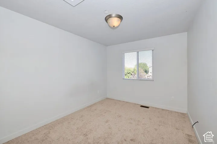 Neutral-toned carpeting, white painted walls, window with blinds, and flush mount lighting
