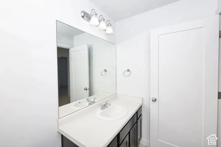 White vanity with integrated sink, chrome faucet, and expansive wall-mounted mirror
