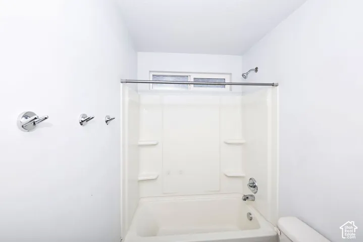 White bathtub and shower combination unit featuring chrome fixtures