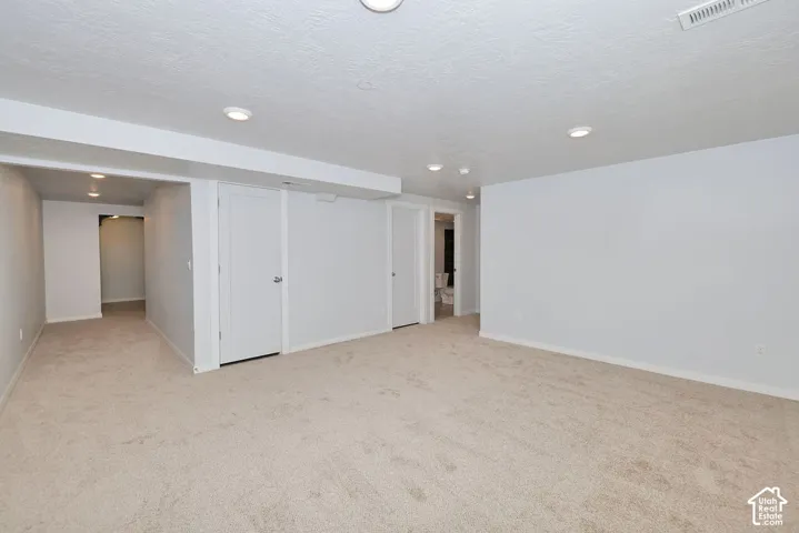 Recessed lighting, light-colored carpeting, white interior doors, and pale wall paint