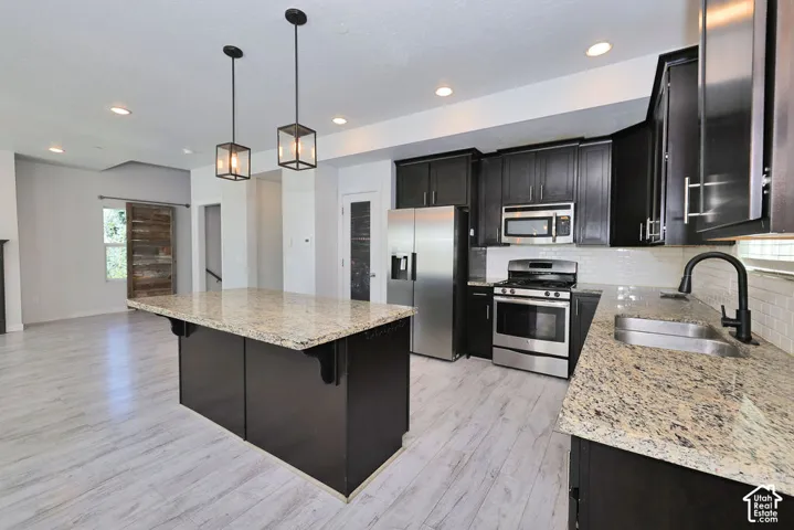 Kitchen featuring dark cabinetry, stainless steel appliances, granite countertops, and white subway tile backsplash