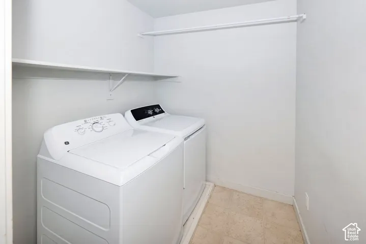 Utility space with tile flooring, an upper storage shelf, and a clothing rod