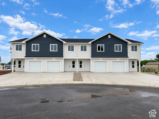 Modern townhome-style residences featuring two-tone exterior siding, white garage doors, and individual entryways