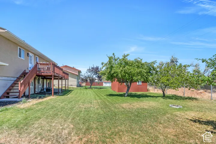 Expansive lawn area with a raised wooden deck and exterior staircase