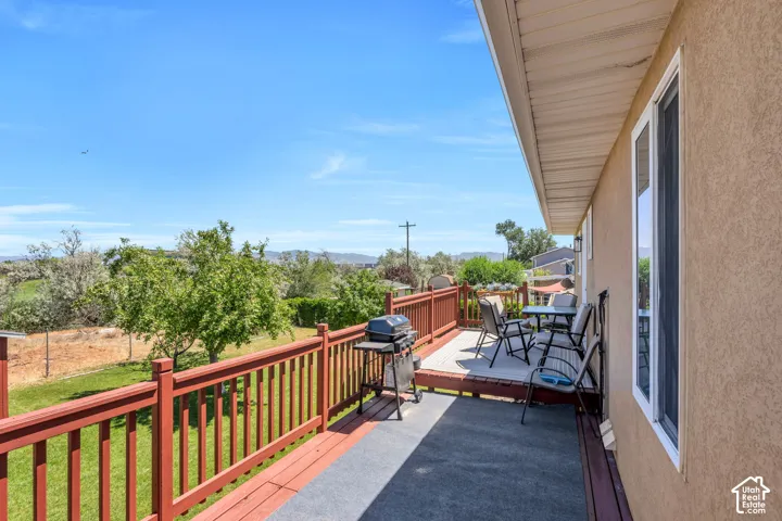 Spacious outdoor deck with a red railing, stucco exterior, and white-framed windows