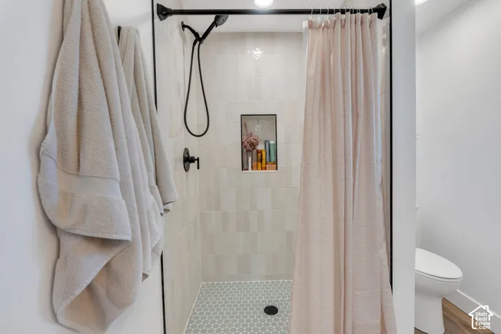 Shower with light-toned tiled walls, a built-in shower niche, and a hexagonal mosaic tile floor